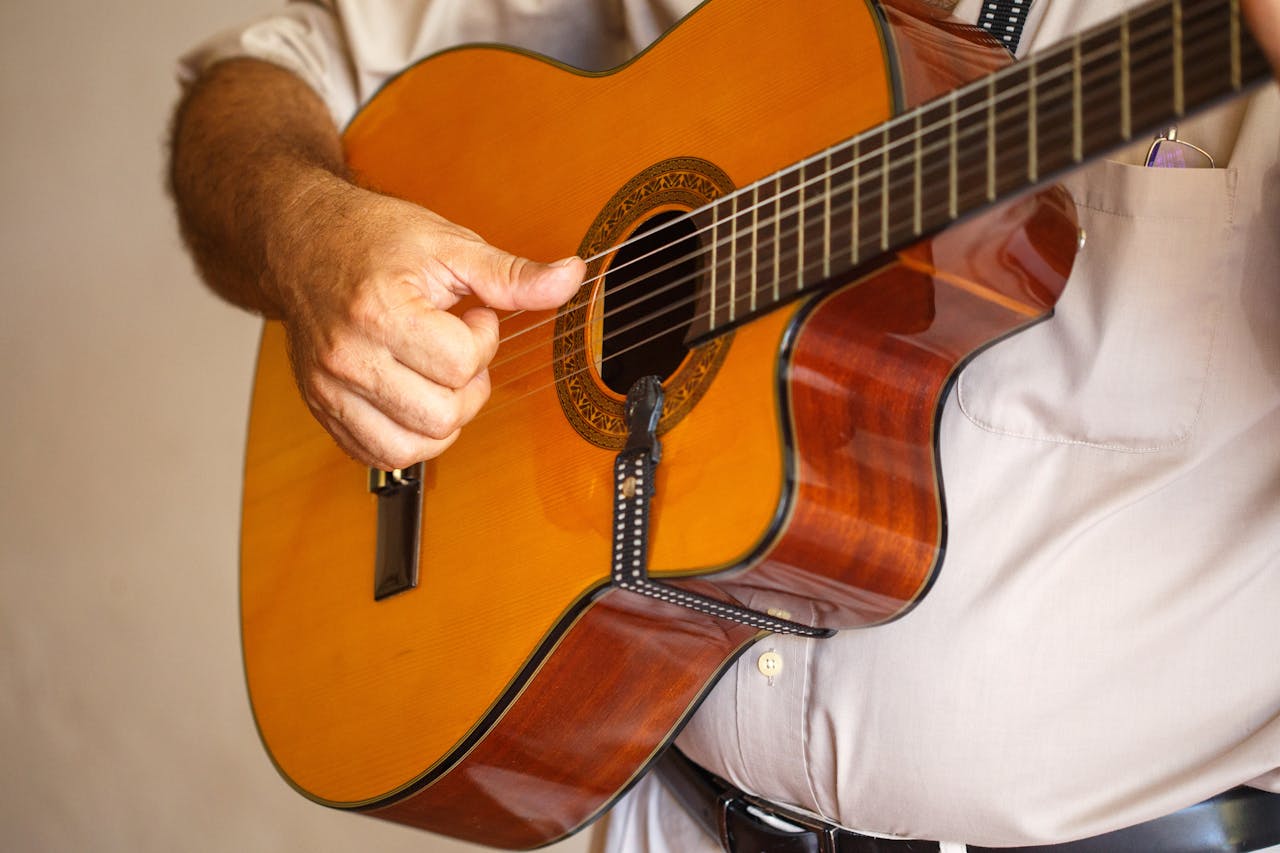 Detailed view of a musician strumming an acoustic guitar indoors.
